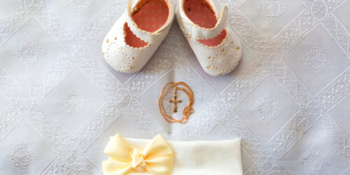 Christening details. On white baby shoes and bandage.